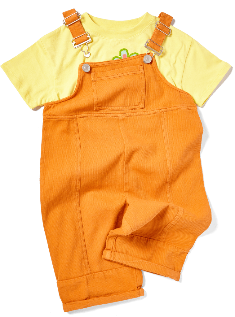 Flat lay product photography of an orange denim kids dungaree set layered over a bright yellow t-shirt with a small graphic, centered on a clean white background.