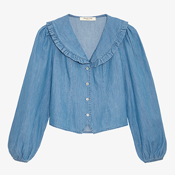 Flat lay e-commerce photography showing the front view of a long-sleeve light blue denim blouse with a ruffled collar on a solid white background.