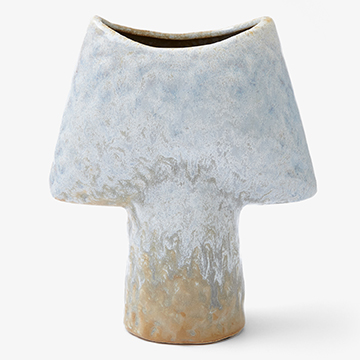 Front view still life product photography of an asymmetrical light blue and beige glazed ceramic vase on a seamless white background.
