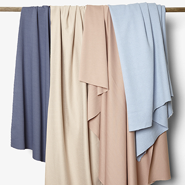 A creative still life composition of hanging, draped pastel and neutral fabrics by Yellow Thread Studio in London