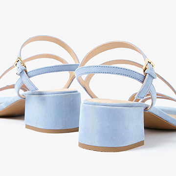 Close-up detail view from behind the light blue sandals focusing on the block heel texture and secure ankle strap stitching.
