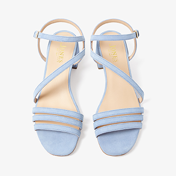Overhead top-down detail shot of light blue strappy sandals showing the footbed branding and alignment of the ankle straps.