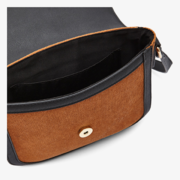 Detail product shot looking inside an open tan suede handbag to showcase the black interior lining and internal compartment layout.
