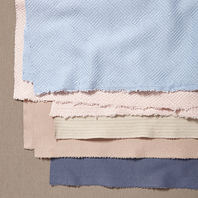 A creative still life composition of layered pastel and neutral fabrics by Yellow Thread Studio in London