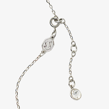 Close-up of the silver spring ring clasp, extender chain, logo tag, and end stone.